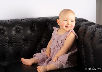 Séance bébé assis sur son canapé noir